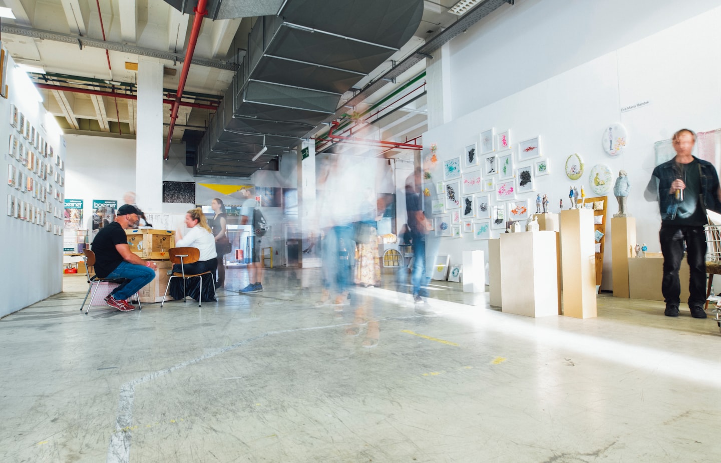 People observing art and sculptures in a modern gallery space.