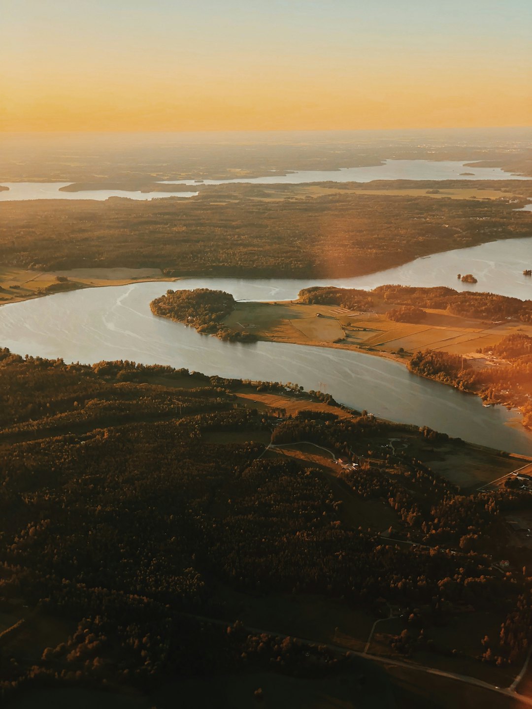 A winding river flows through dense forests and cultivated fields.