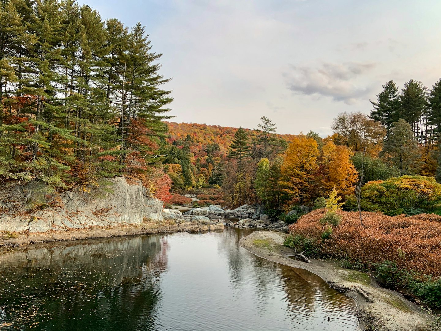 River flows through rocky autumn forest landscape.