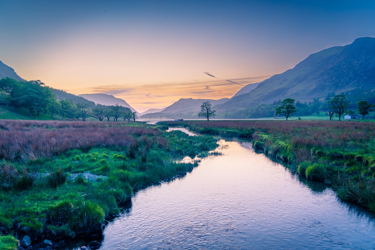A winding river flows through a valley surrounded by mountains.